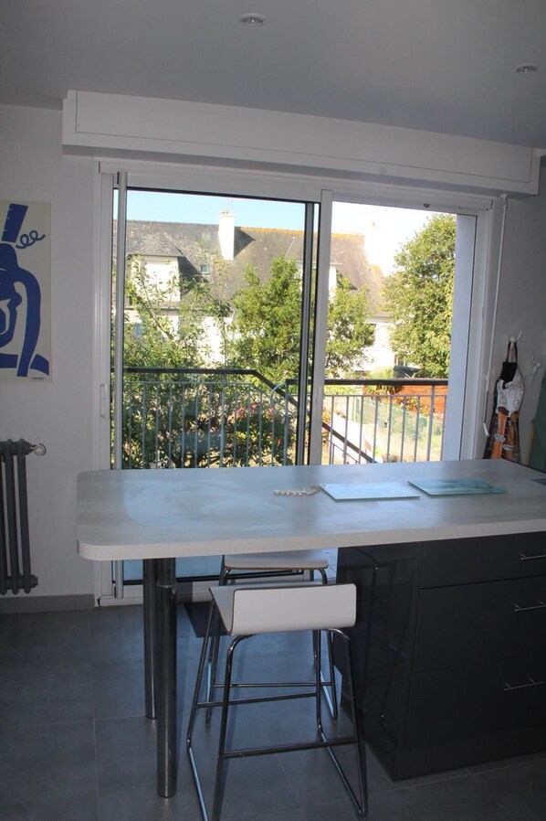 A modern kitchen with a large window, a white countertop, and a black cabinet.