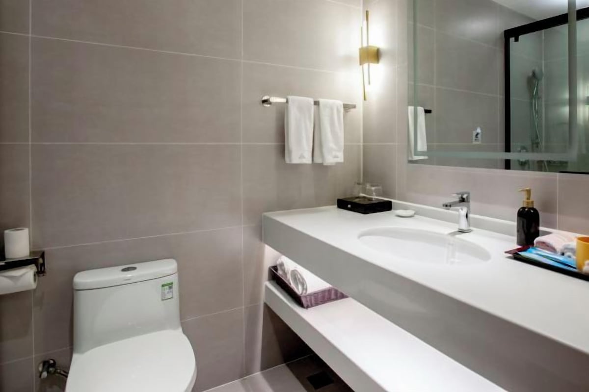 A modern bathroom with a toilet, sink, and mirror.