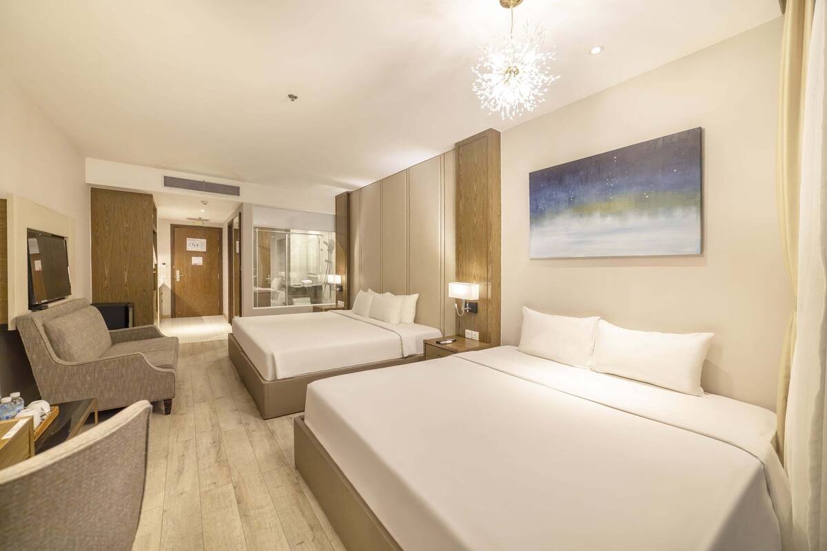 Habitación de hotel con dos camas, un sofá, un televisor, un baño y un cuadro en la pared.