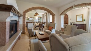 Een ruime woonkamer met een open haard, comfortabele zithoek en een open indeling die aansluit op een eetgedeelte.