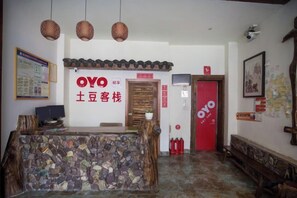 A reception area with a stone counter, hanging lights, and a red door labeled 'OYO.' - Zhangjiajie Potato Inn Baofeng Branch (Zhangjiajie)