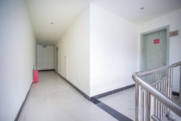 A corridor with a metal railing, a door with a sign, and a red object on the left. - Zhangjiajie Potato Inn Baofeng Branch (Zhangjiajie)