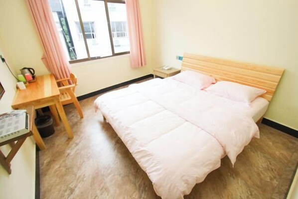 A room with a bed, a wooden desk, a chair, a window with curtains, and a nightstand. - Zhangjiajie Potato Inn Baofeng Branch (Zhangjiajie)