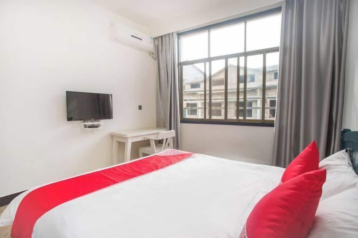 Une chambre d’hôtel avec un lit, un bureau, une télévision et une fenêtre avec des rideaux.