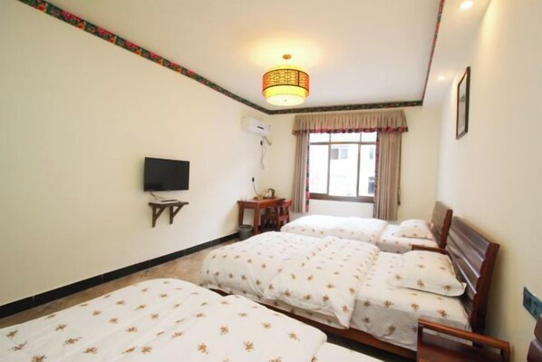 A hotel room with two beds, a television, a desk with a lamp, and a window with curtains. - Zhangjiajie Potato Inn Baofeng Branch (Zhangjiajie)