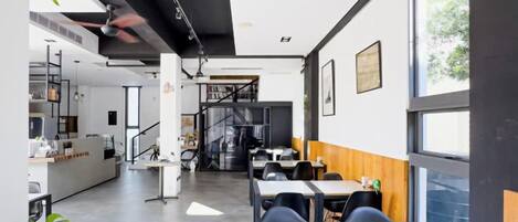 Un interior moderno con zona de cocina, mesas de comedor y una escalera que lleva a un nivel superior.