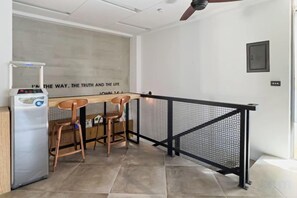 A room with a kitchenette, two wooden chairs, a small table, and a black metal railing. - Pathway Inn (Penghu)