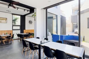 A modern interior with tables and chairs, large windows, and a view of the outside. - Pathway Inn (Penghu)
