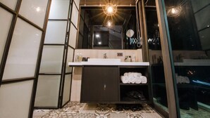 A modern bathroom with a large mirror, a sink, and a shower area. - Pathway Inn (Penghu)