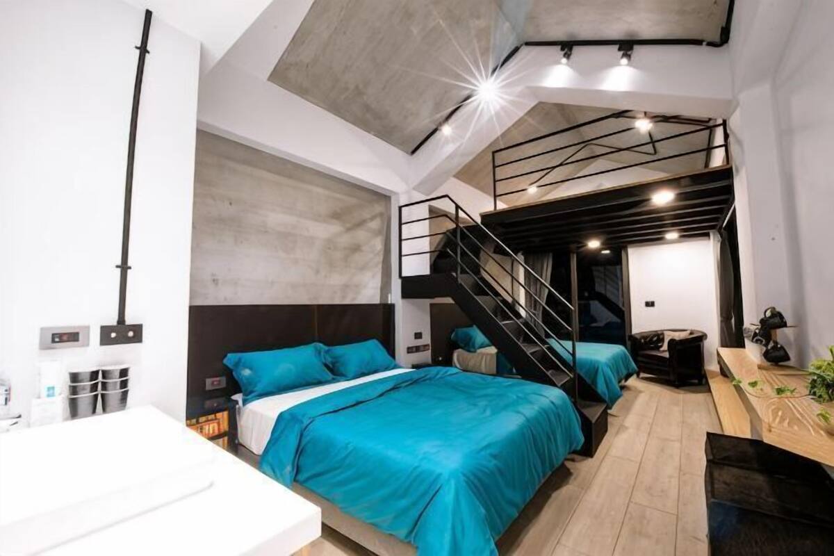 A modern bedroom with bunk beds, a desk, and a staircase.