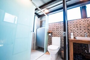 A bathroom with a toilet, sink, and patterned wall tiles. - Pathway Inn (Penghu)