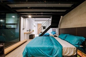 Quarto moderno com uma cama, uma escrivaninha e uma escada que leva a um andar superior.