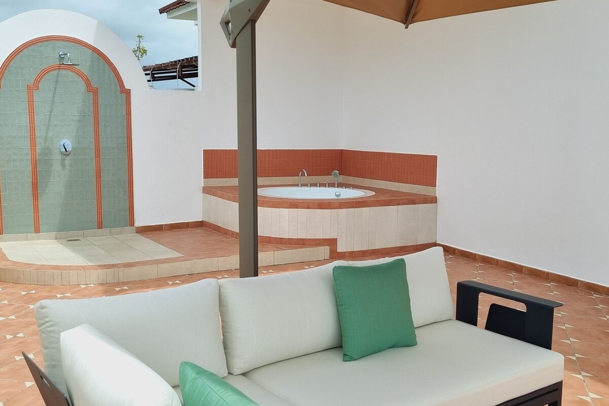 A patio with a sofa, a hot tub, and a door.