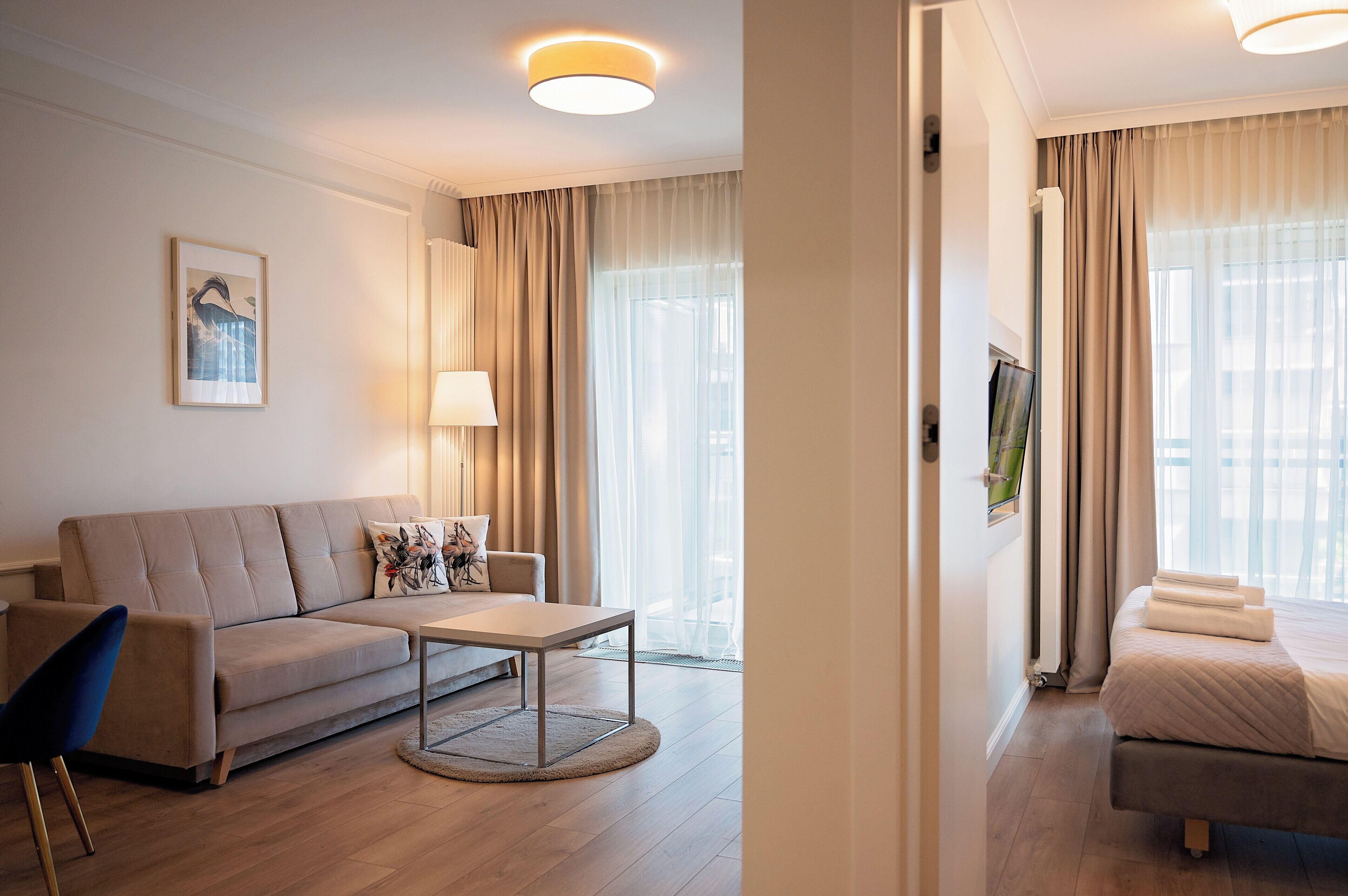 Ett modernt hotellrum med en soffa, ett litet bord, en säng och en tv.