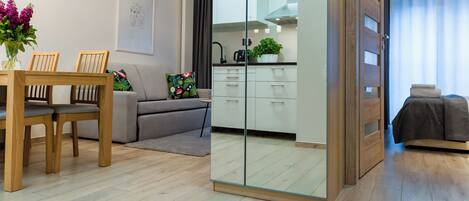 A modern living room with a dining table, sofa, and kitchen area.