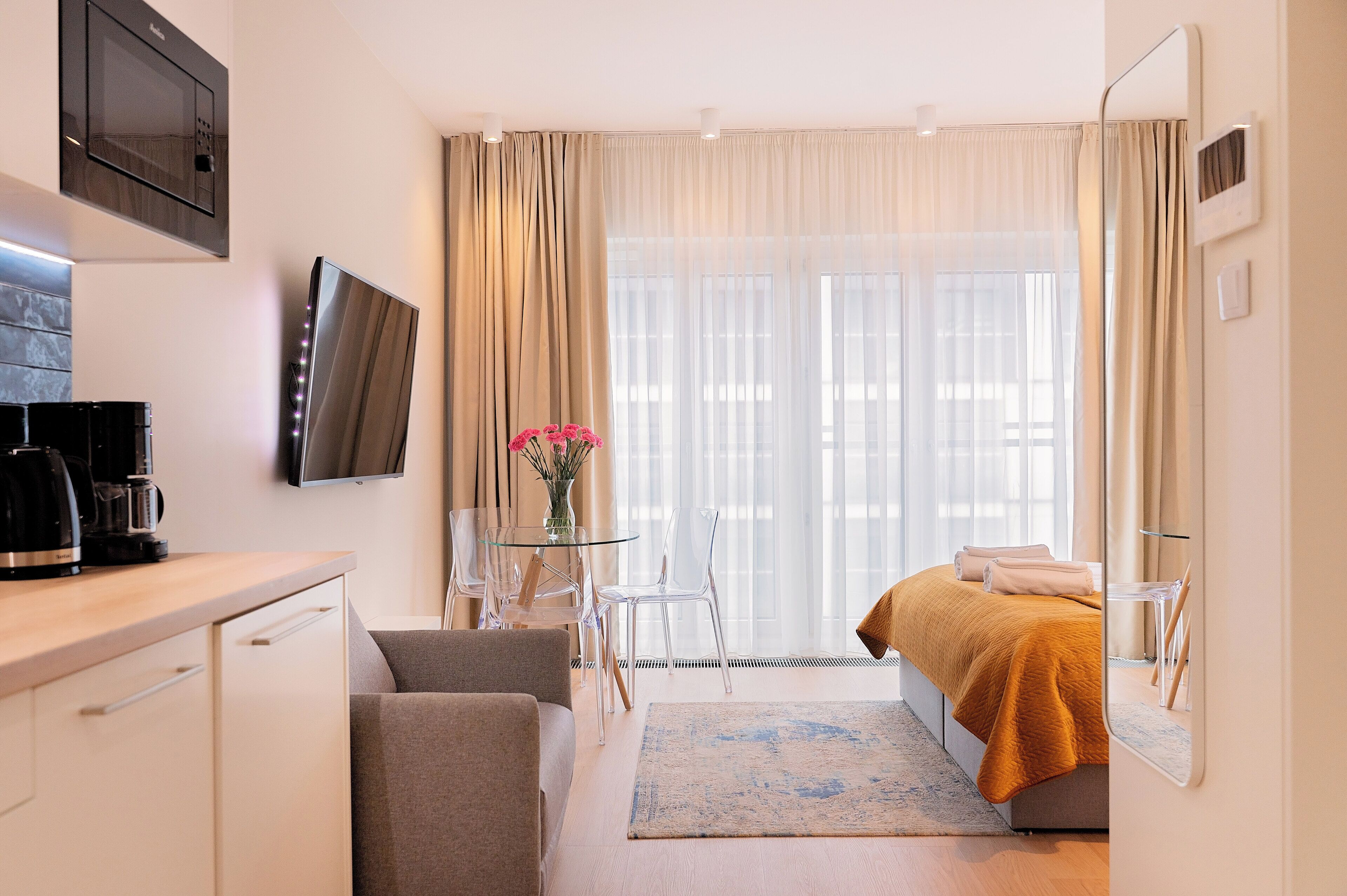 Une chambre d’hôtel avec un lit, un bureau doté d’une machine à café, une télévision et une fenêtre avec des rideaux.