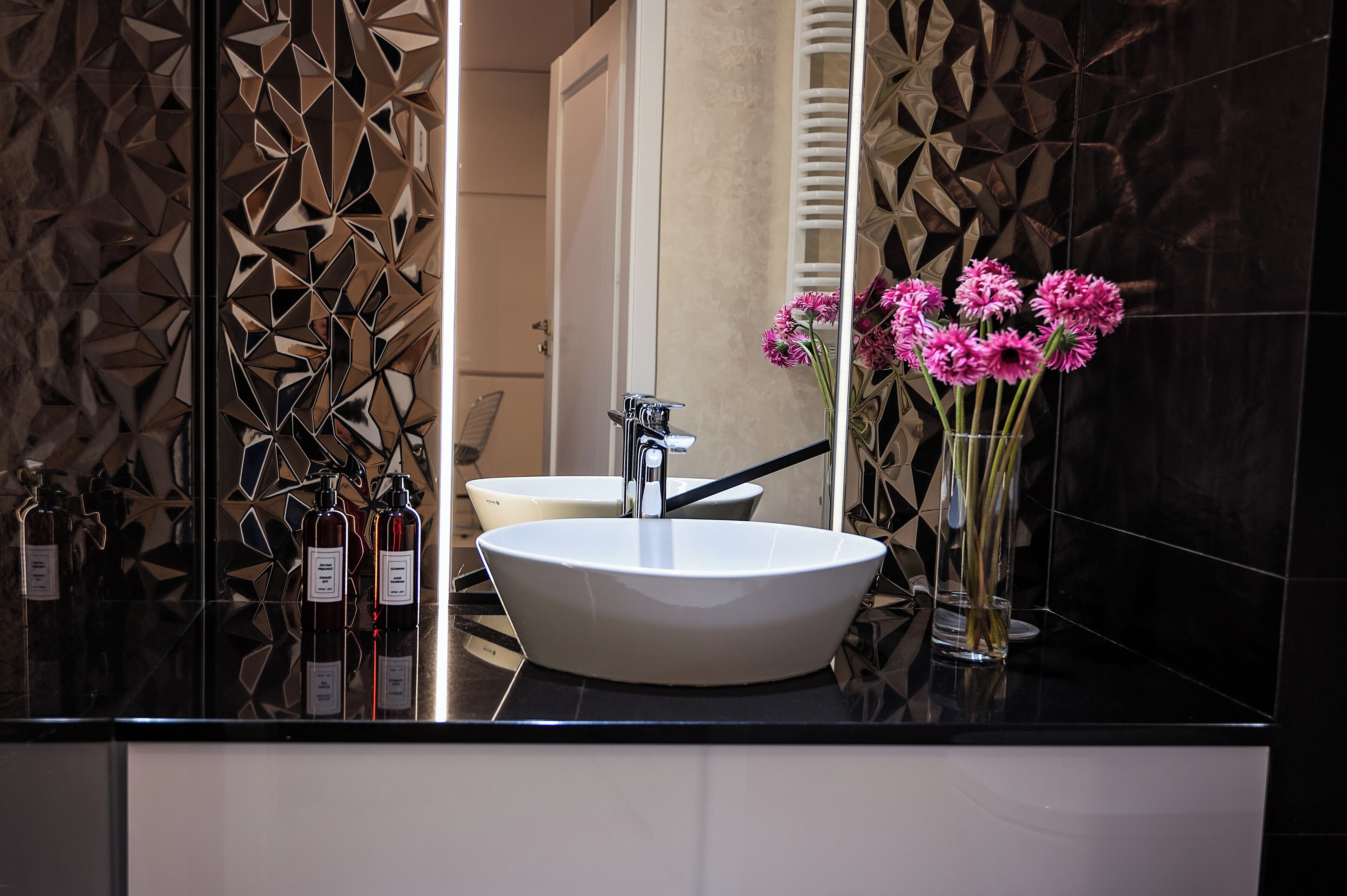 A modern bathroom with a large white sink, a mirror, and decorative wall panels.