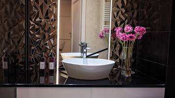 A modern bathroom with a large white sink, a mirror, and decorative wall panels.