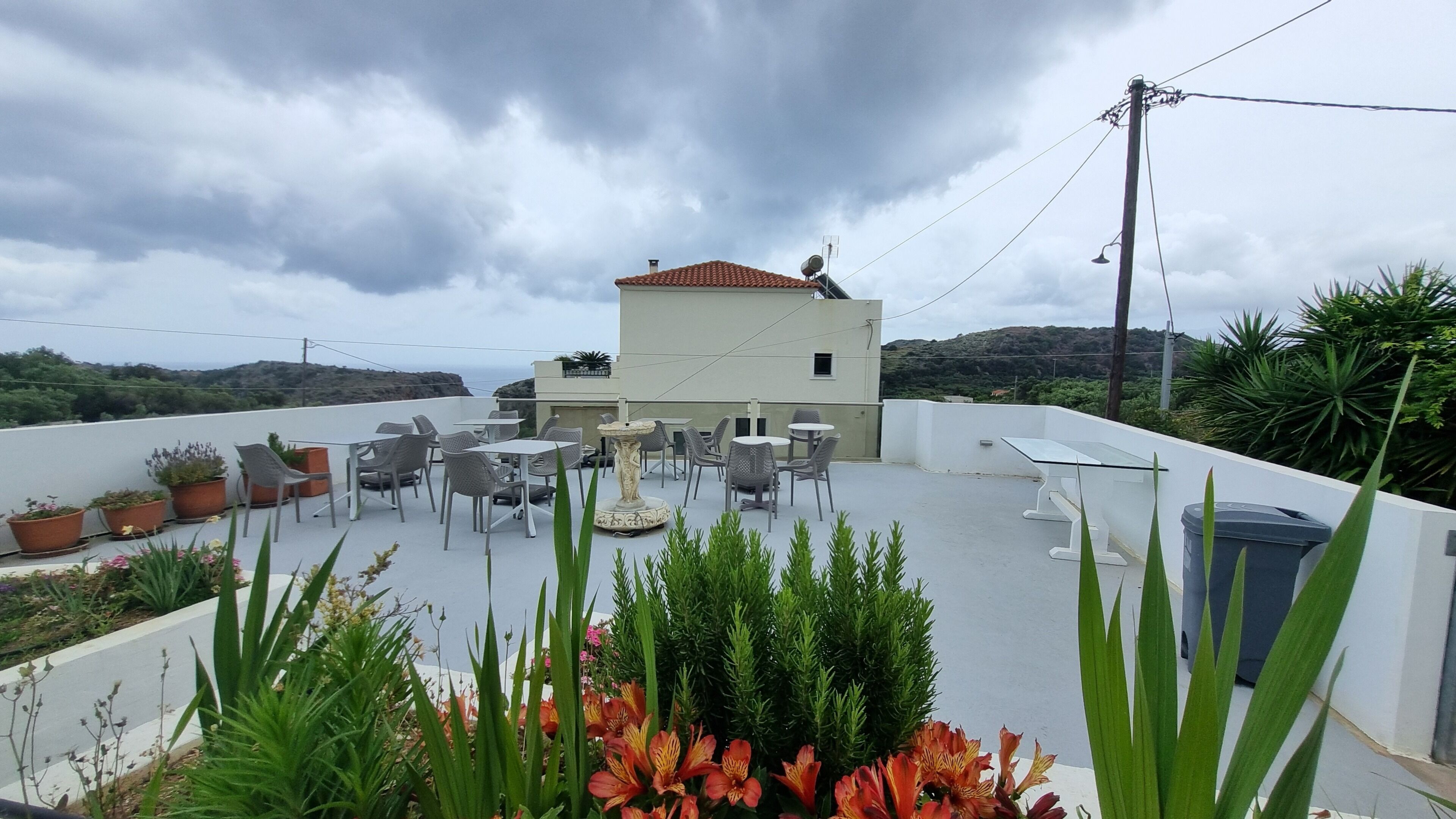 A rooftop terrace with outdoor seating, potted plants, and a view of the surrounding landscape.