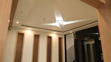 A modern interior with a marble floor, wooden panel accents, and a ceiling with recessed lighting.