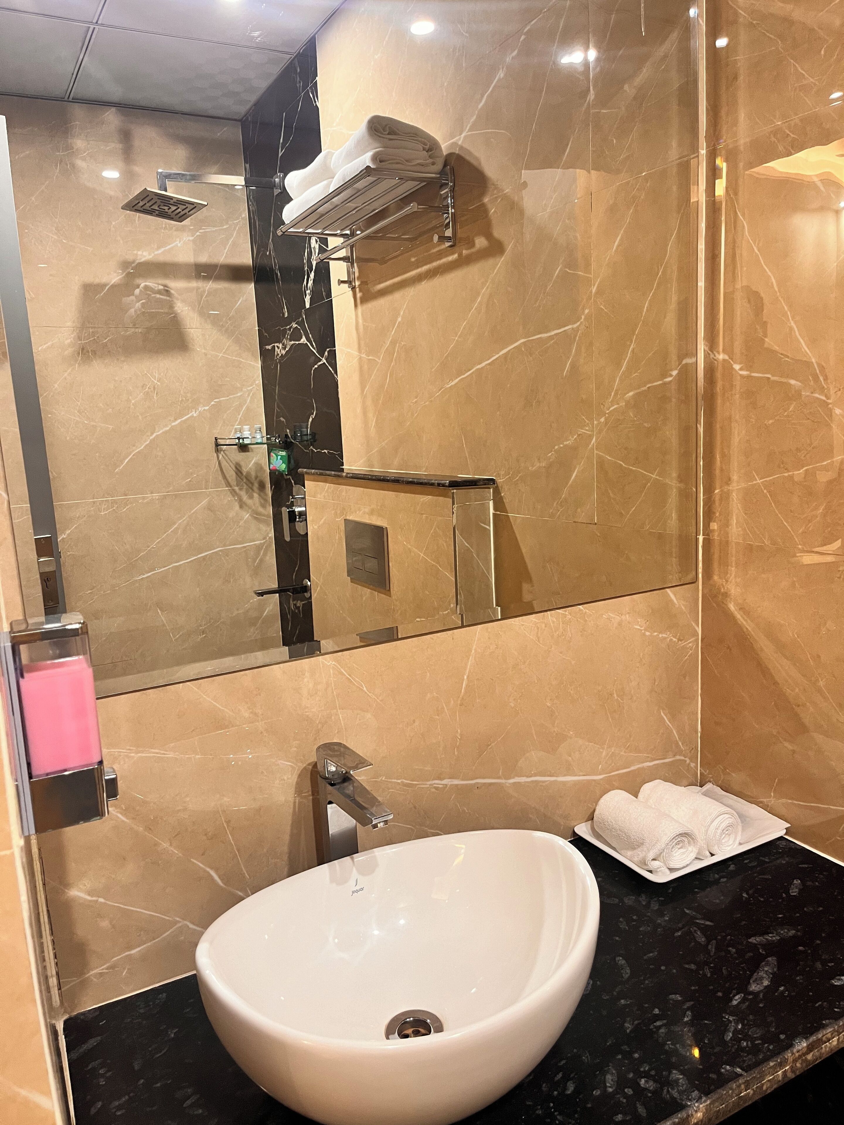 A bathroom with a large mirror, a white sink, and a towel rack.