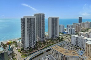 A high-rise hotel with multiple floors, a swimming pool, and a view of the ocean.