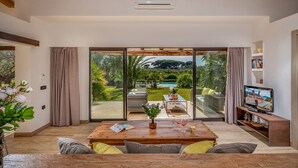 A spacious living room with a large sliding glass door leading to a private outdoor area with a pool and greenery. - Villa Pineta 6 Emma Villas (Castelvetrano)