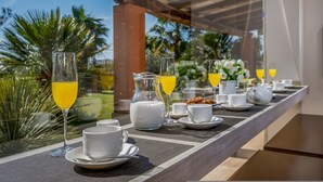 A breakfast table with white cups, saucers, and a pitcher of milk, set against a view of palm trees and a clear sky. - Villa Pineta 6 Emma Villas (Castelvetrano)