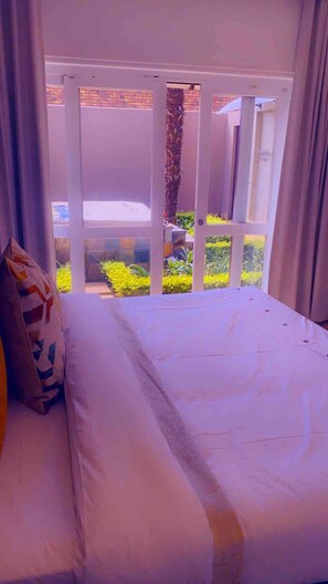 A bed with a view of a garden through a glass door. - Or Tambo Airport Holiday Home (Boksburg)