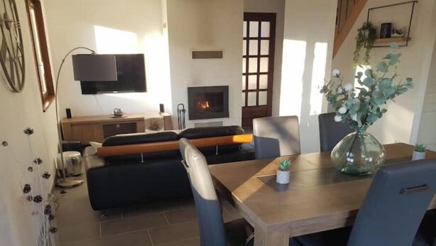 Ein modernes Wohnzimmer mit Kamin, einem Esstisch und blauen Stühlen.
