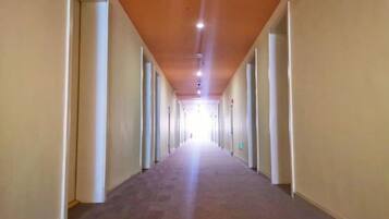 Un pasillo largo y estrecho con puertas a ambos lados, que conduce a habitaciones individuales.