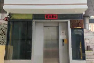 Una entrada de edificio con puerta de vidrio y un letrero rojo encima.