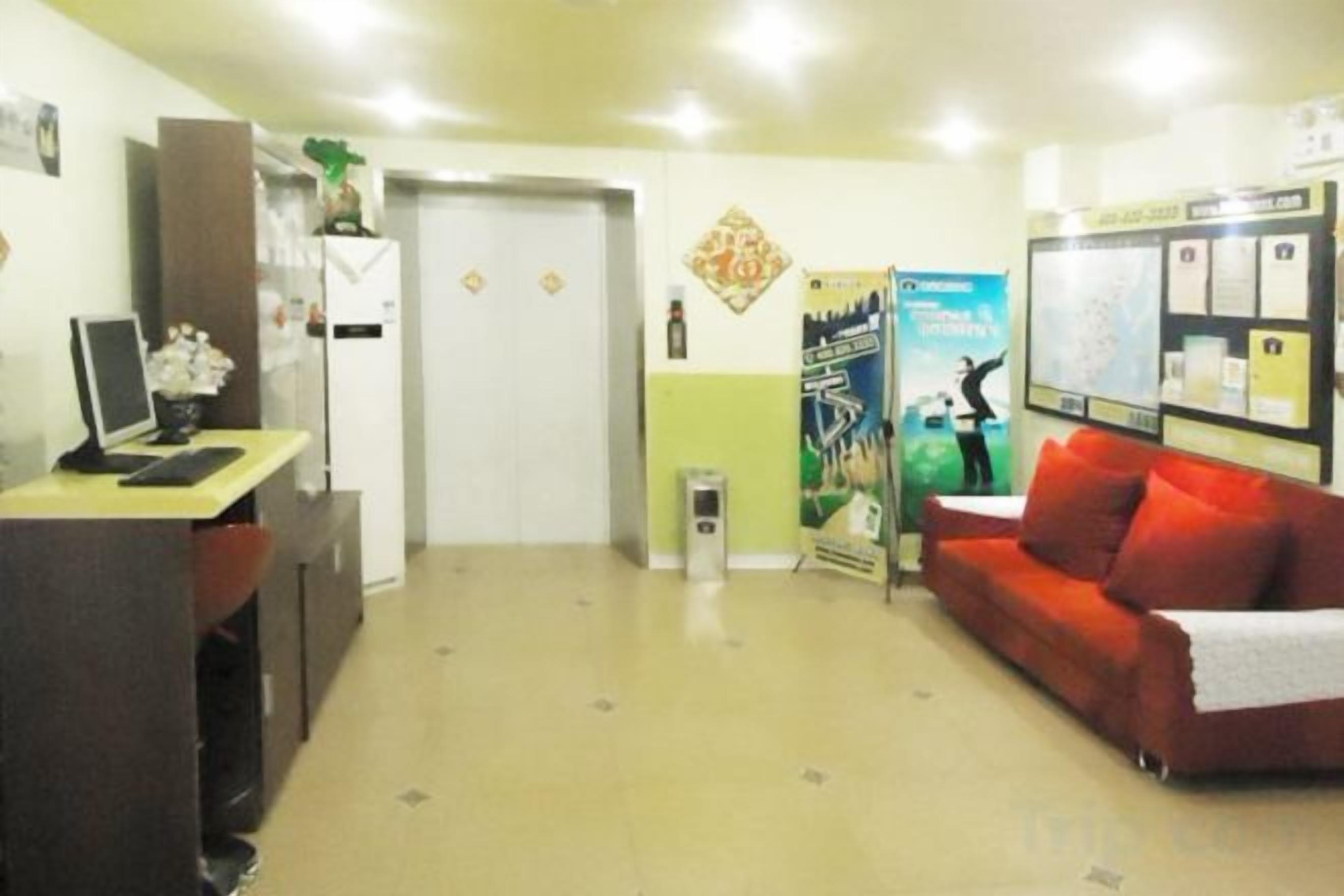 A reception area with a desk, a red couch, a door, and a bulletin board.