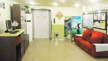 A reception area with a desk, a red couch, a door, and a bulletin board.