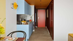 Pieni hotellihuone, jossa on minikeittiö, ruokailutila ja sänky.