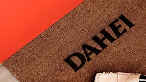 A brown doormat with the name "DAHEI" in black letters, placed on a wooden floor next to a pair of white shoes with black soles. - Cozy Studio Apartment for 2 (København)