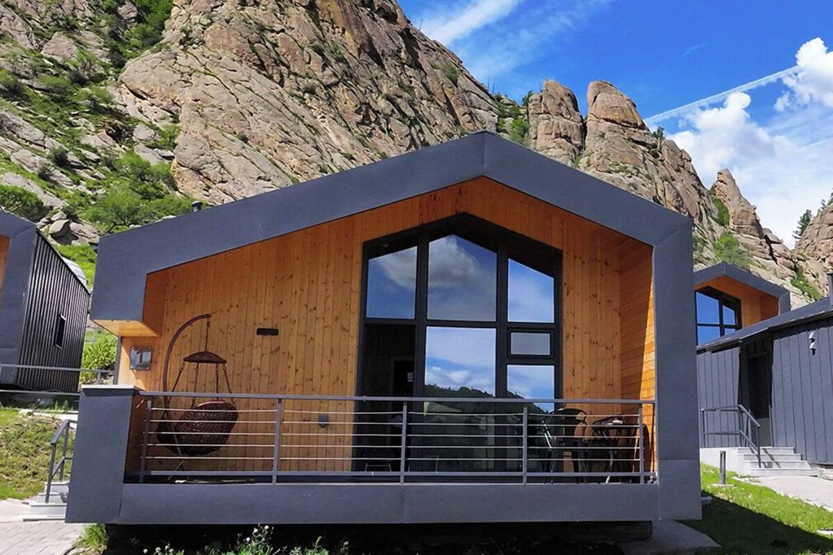 Una cabana moderna amb una finestra gran, un balcó i façana de fusta.