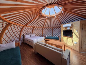 A cozy interior of a round wooden structure with a bed, sofa, and a small table. - Energy Hills Resort (Ulaanbaatar)
