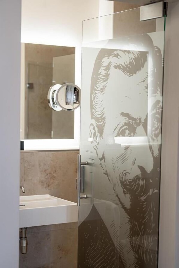 A modern bathroom with a glass shower enclosure, a white sink, and a large mirror. - Maxim Suites by Elias Holl (Augsburg)
