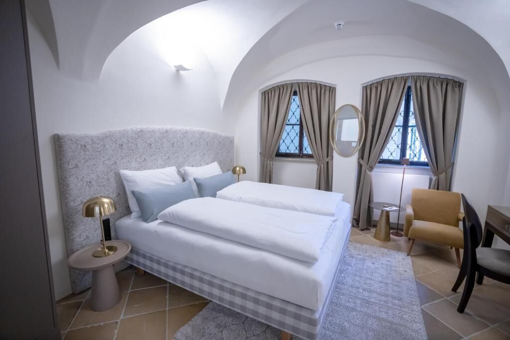 A bedroom with a large bed, a bedside table with a lamp, a chair, and a small table.