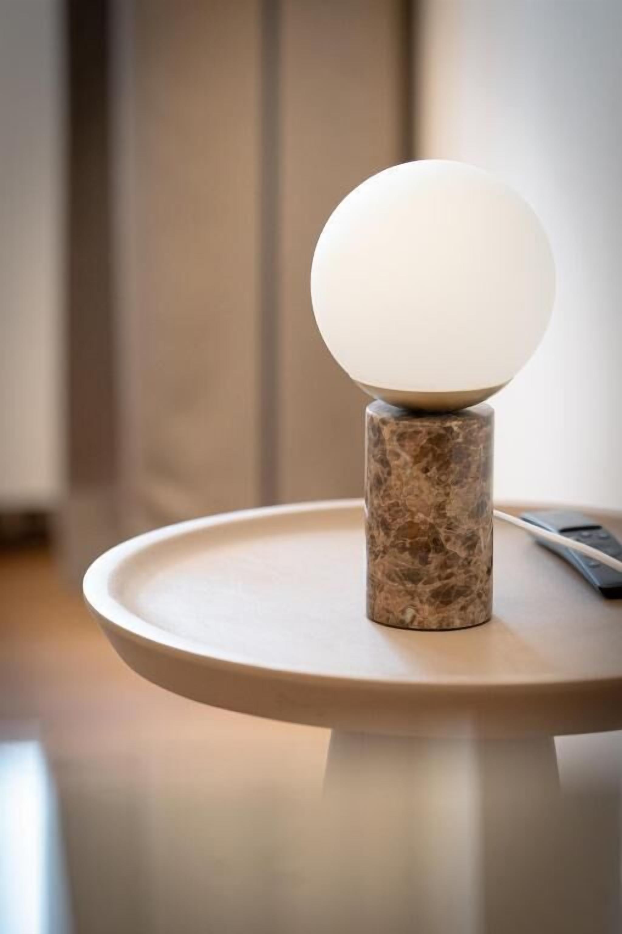 Una mesa con base de mármol y un objeto esférico blanco en la parte superior.
