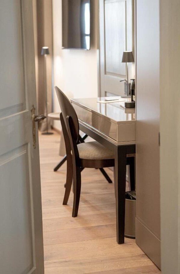 Una habitación moderna con piso de madera, una mesa de vidrio y una silla de madera oscura.