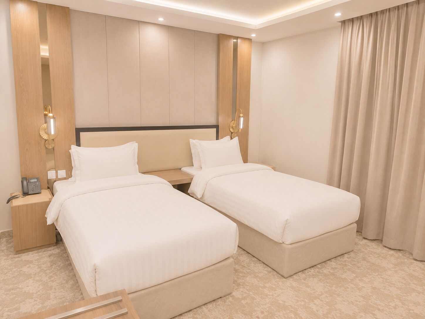 Ein Hotelzimmer mit zwei Einzelbetten, einem Nachttisch mit Telefon und einer Wandleuchte.