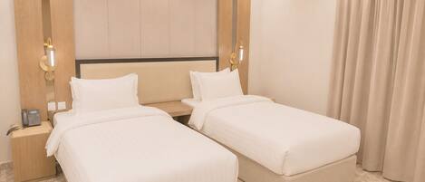 Ein Hotelzimmer mit zwei Einzelbetten, einem Nachttisch mit Telefon und einer Wandleuchte.