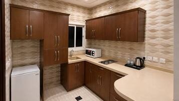 A compact kitchen with wooden cabinets, a built-in microwave, and a sink.