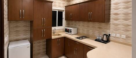 A compact kitchen with wooden cabinets, a built-in microwave, and a sink.