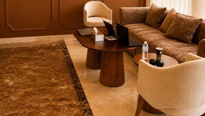 A modern living room with a flat-screen TV, a sofa, a coffee table, and a chair. - Jwana Hotel (Riyadh)