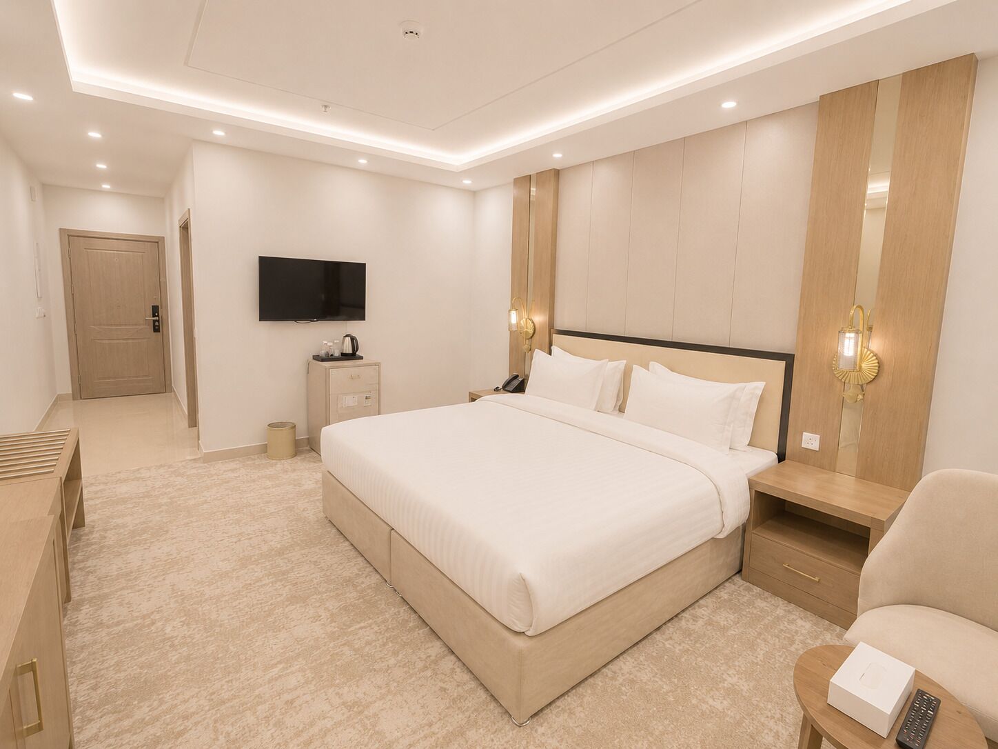 A modern hotel room with a large bed, bedside tables, a TV, and a wardrobe.