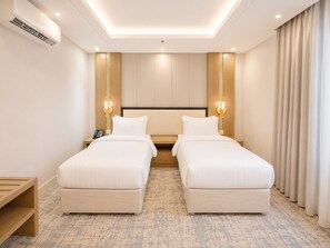 Habitación de hotel con dos camas, una mesita de noche de madera, un teléfono y una lámpara fijada a la pared.