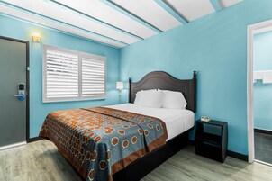 Un dormitorio con cama, mesita de noche, ventana con persianas y puerta.